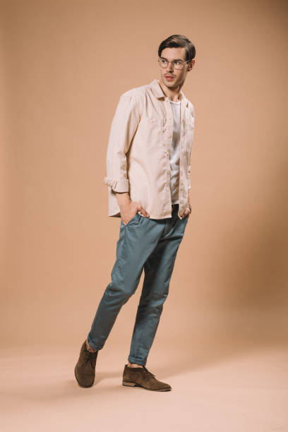 istock confident man in glasses standing with hands in pockets  on beige background 1142827716
