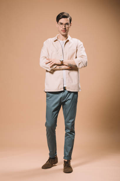 istock confident man standing with crossed arms  on beige background 1142827721