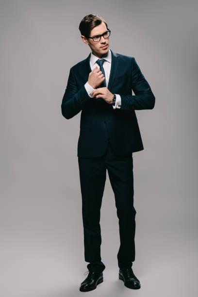 istock confident businessman standing in suit on grey background 1142827835
