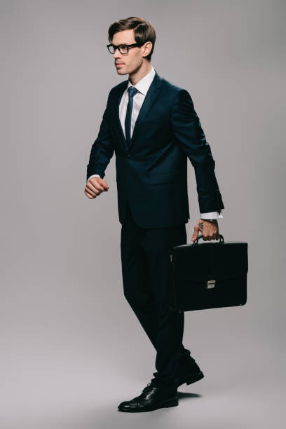 istock confident businessman in suit walking with briefcase on grey background 1142827848