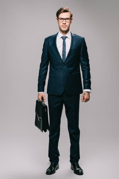 istock confident businessman in suit holding briefcase on grey background 1142827849
