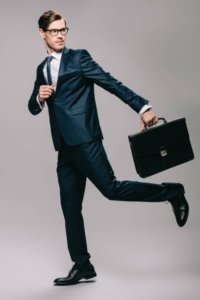 istock handsome businessman in suit running with briefcase on grey background 1142827854