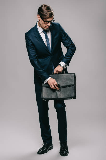 istock handsome businessman in glasses opening briefcase on grey background 1142827860