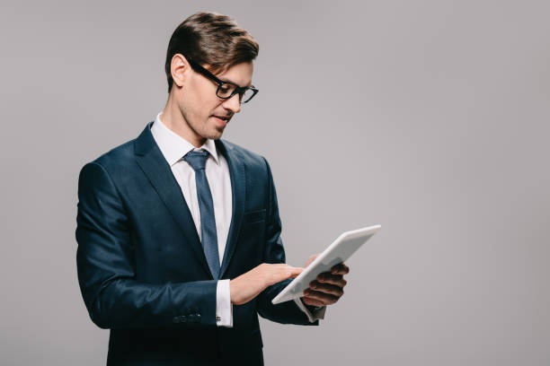 istock handsome businessman in glasses using digital tablet isolated on grey 1142827867