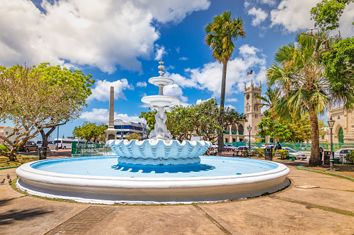 White empty fountain with sculpture in the city center of Bridgetown, Barbados. Bright and colorful image with blue sky and white clouds on a summer day.