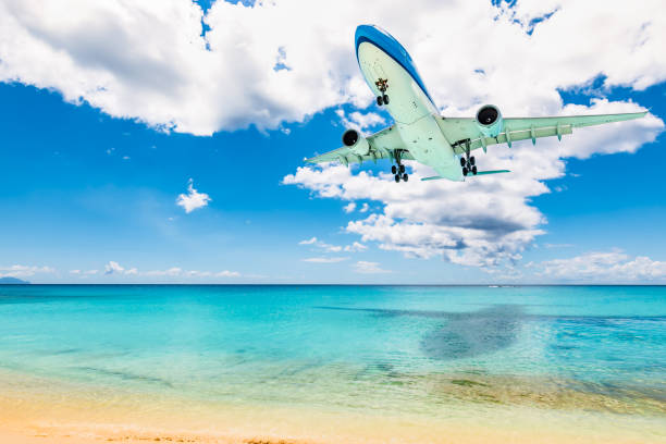 Air transportation and travel background. Airplane above sea and beach. Summer holiday concept with aircraft, turquoise Caribbean Sea and white sand Maho beach in St Maarten. saint martin caribbean stock pictures, royalty-free photos & images