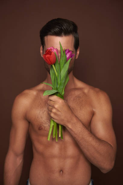 istock Young macho man close face by tulips bunch 1142828466