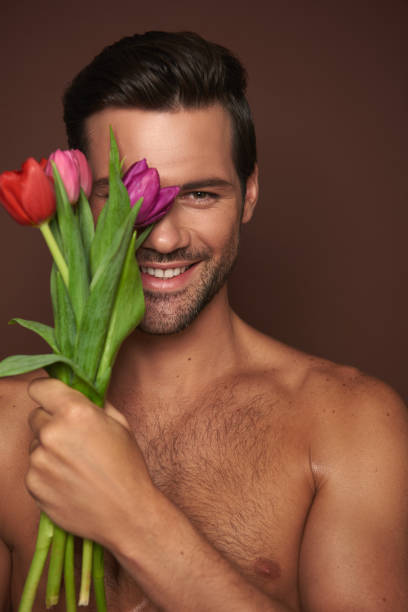 istock Happy young man close one eye by tulips bunch 1142828486
