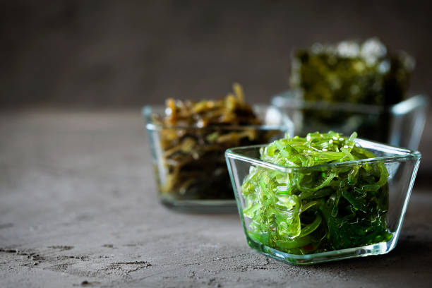 traditionelle japaner chuka wakame algensalat und knusprig geröstete nori-platten in glasschale auf dunklem hintergrund aus nächster nähe mit kopierraum. asiatische japaner chuka - close up green plate salad stock-fotos und bilder