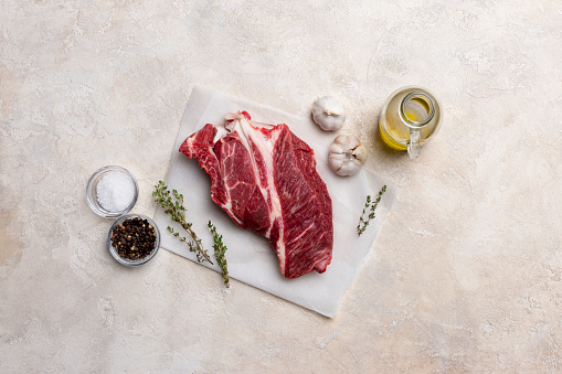 Fresh beef meat on white background with olive oil, herbs and spices. Free space for text. Concept of fresh food
