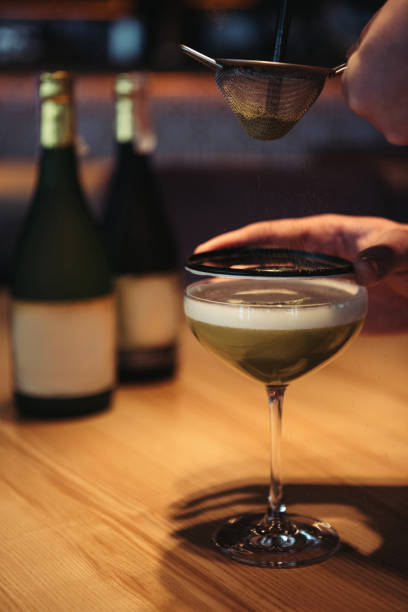 selective focus of bartender preparing alcoholic cocktail using sieve