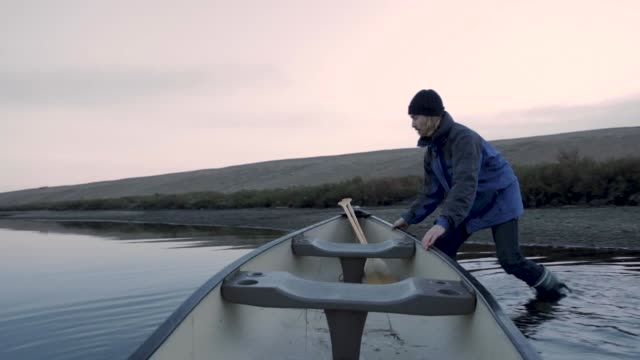 Young man canoeing on calm flat water on the South Coast of England at dusk