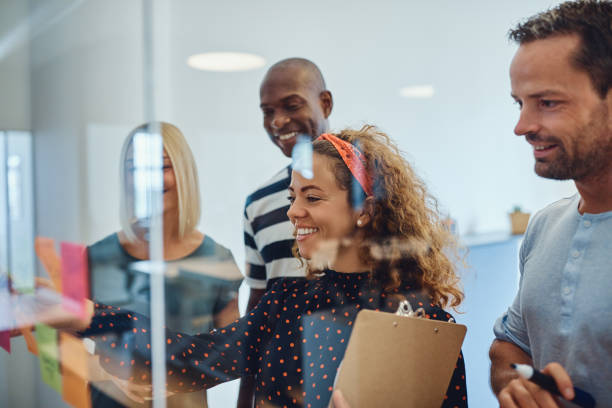 istock Group of smiling designers brainstorming together with sticky notes 1142835780