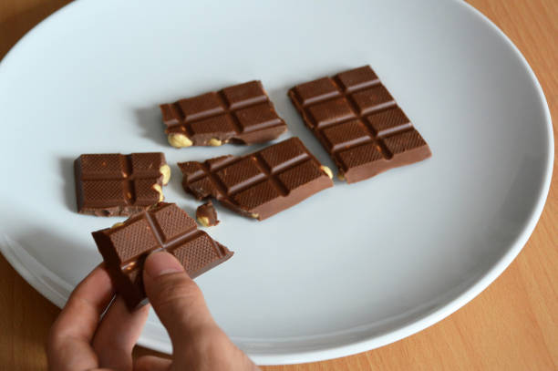 istock Male hands cracked chocolate bar on a plate 1142836522