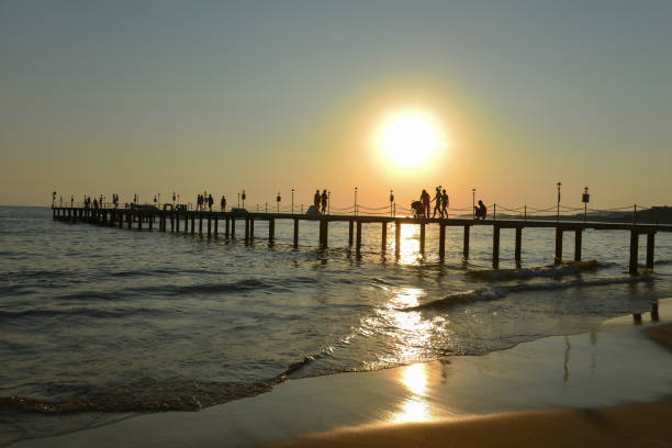 istock sea pier, people, walking and sunset time 1142838922
