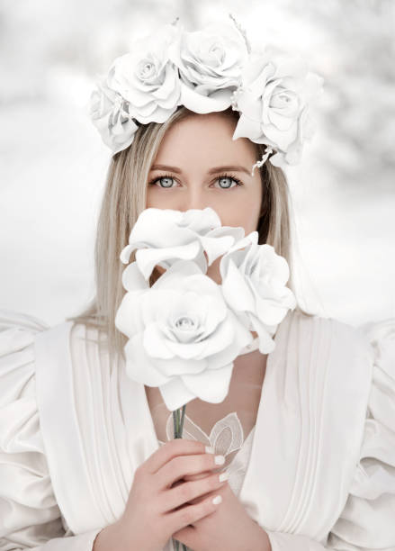 A beautiful young Ukrainian woman dressed in a blue embroidered dress with a large beautiful flower wreath on her head closed her eyes and folded her arms in prayer.
