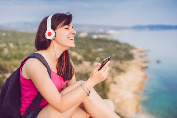 Happy, young woman, listening to the music and enjoying the beautiful view. Thassos, Greece.