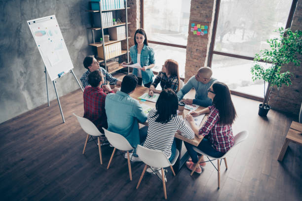 istock Pretty serious manager lady presenting explaining coworkers professionals development successful strategy using documents in comfort office dressed in casual shirts 1142841463