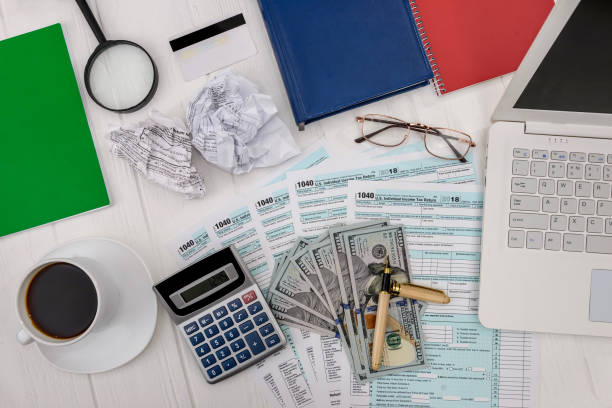 istock 1040 form with dollars, calculator and laptop 1142841604