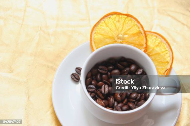 Cup And Saucer Coffee Beans Slices Of Dried Orange On A Gold Background Stock Photo - Download Image Now