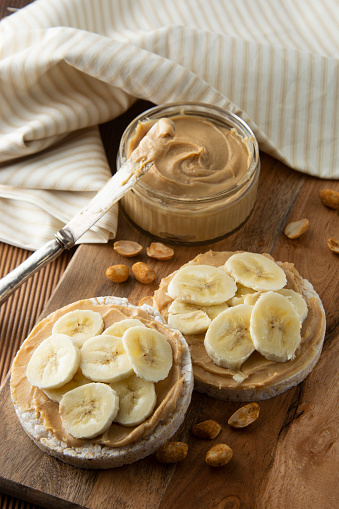 Proteine food - Peanut butter and banana, rice cakes, healthy, dietary food. Wooden background