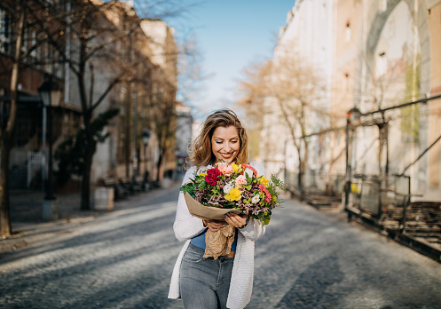 Young walking city streets with flower bouquet