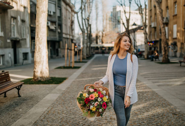istock Young walking city streets with flower bouquet 1142849404