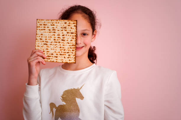 matzah またはマッツァシットを保持している若い女の子.ユダヤ人の祝日過越の招待状やグリーティングカード。選択的フォーカス。スペースをコピーします。 - matzo passover food judaism ストックフォトと画像