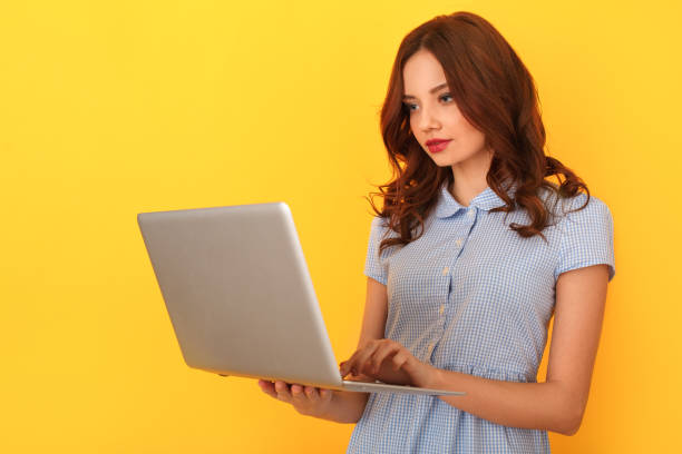 istock Young woman studio isolated on yellow working on laptop 1142850903
