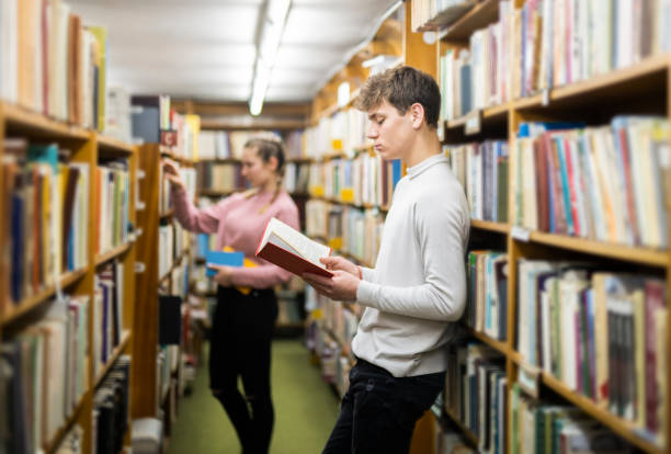 istock Smiling couple studying together in a library. 1142852490