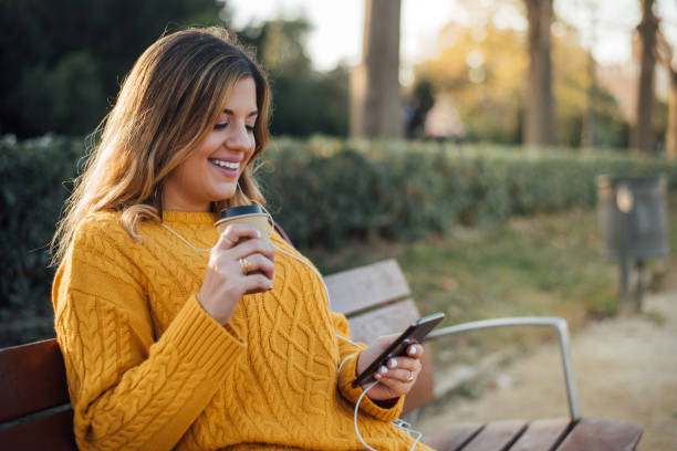 istock Girl sitting at the park and using phone 1142854124