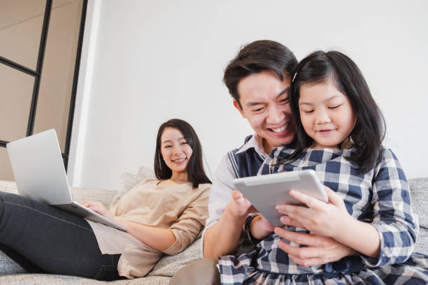 happy asian family spending time together at home playing game, tablet for education - father digital tablet asian ethnicity daughter imagens e fotografias de stock