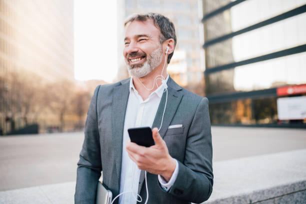 istock Man using mobile phone and in-ear headphones 1142860798