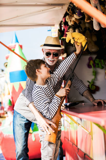 istock Little boy with grandfather having fun at amusement park 1142861053