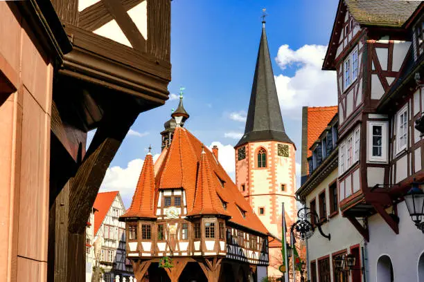 Michelstadt, Germany, 03/31/ 2019: The Market Square with the historical Town Hall. The town hall was built in a late gothic style in the year 1484. Behind the town hall the tower of the late gothic church can be seen.