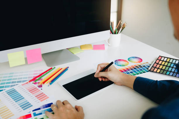 istock Freelance creative designers working on desk using digital graphic tablet and drawing with pen in modern home office. 1142862805