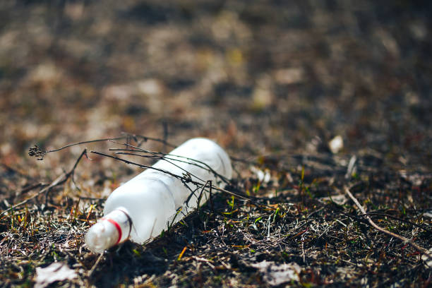 istock Empty white glass bottle lying on grass in early spring, polluted, conservancy. rubbish after last snows of winter 1142864929