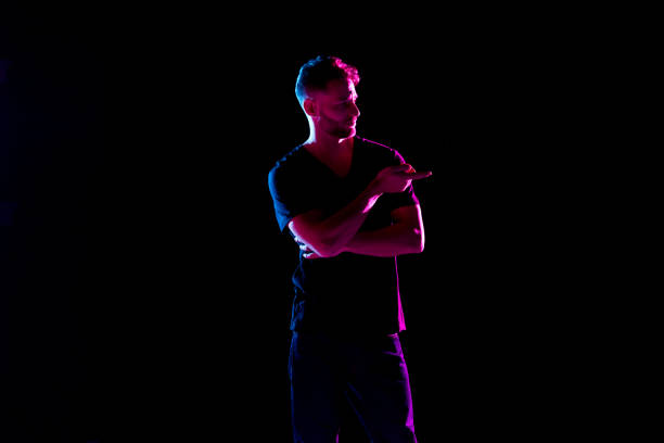 istock Handsome man with black shirt with colored gel lighting 1142866612