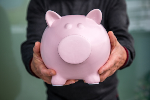 Senior Man holding Piggy Bank in his hands.