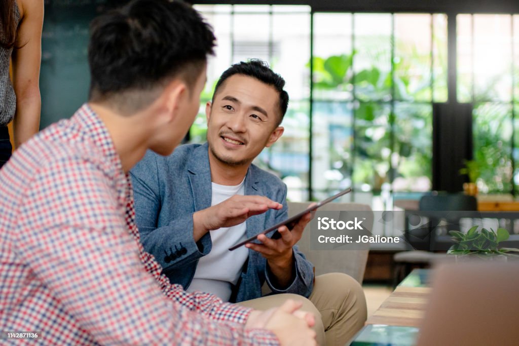 Coworkers having an informal meeting in a modern office Coworkers having an informal meeting in a modern office. Hong Kong 2019 Meeting Stock Photo