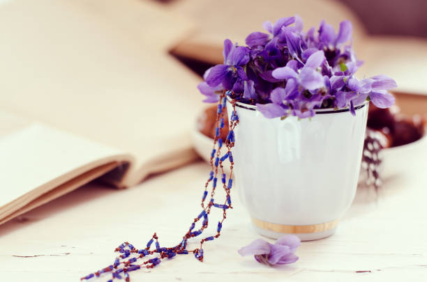 istock Still life with violet in white cup, old books. Romantic spring floral background. 1142877663