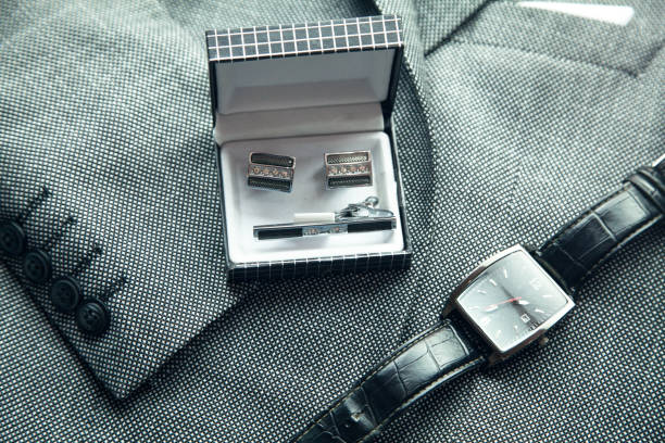 Cufflinks with wristwatch in suit background.
