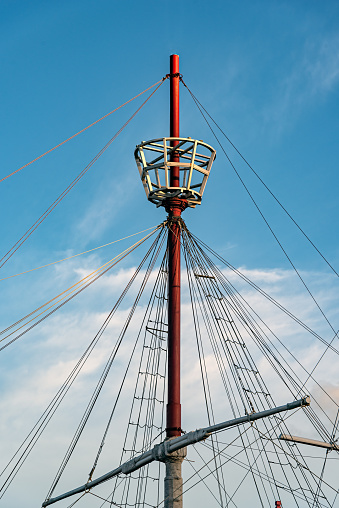 Mástil de un barco con sus cuerdas, su cola para el reloj y un hermoso cielo nublado detrás photo