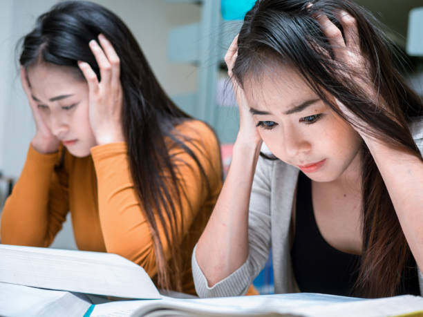 istock Two Female student reading a book for the exam or doing homework.young asian college student at hard exam. 1142886398