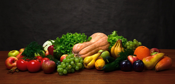 Vegetables and fruits on the oak table and on wooden background. Variety of organic products. Apples, pears, grapes, tomatoes, pumpkin, plum, lettuce, citrus