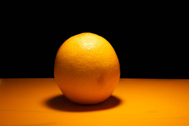 istock orange on orange surface illuminated by warm light on black background. 1142888269