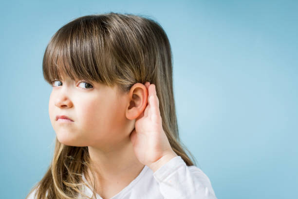 istock Toddler girl with hearing problem on light blue background. Close up, copy space. 1142890897