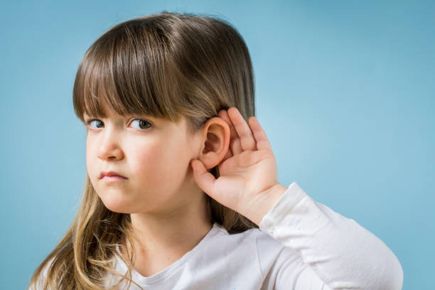 istock Toddler girl with hearing problem on light blue background. Close up, copy space. 1142892142