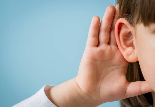 little girl with hearing problem on light blue background. close up, copy space. - young ears imagens e fotografias de stock