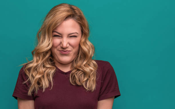 istock A young woman is squinting a sour grimace while standing against blue background. 1142892329